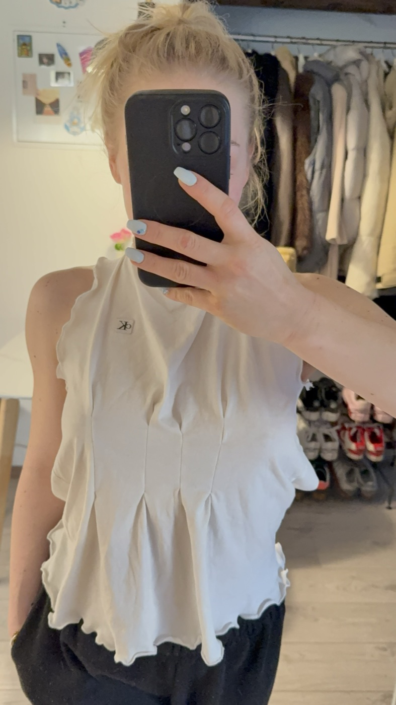 White sleeveless top reworked with front pleats and lettuce hems